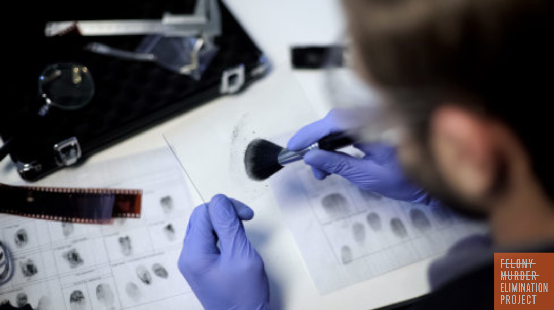 a forensic scientist is dusting an item for fingerprints, with two fingerprint sheets on the table nearby (Photo: Ievgen Chabanov/Adobe Stock)